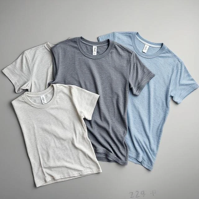 Flat lay of eco-friendly T-shirts made from recycled cotton and poly yarn in heather grey and oatmeal tones - sustainable apparel producer India.